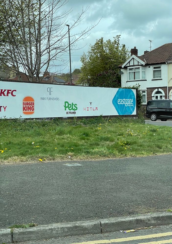 A photo of a billboard showing various logos including Tesla