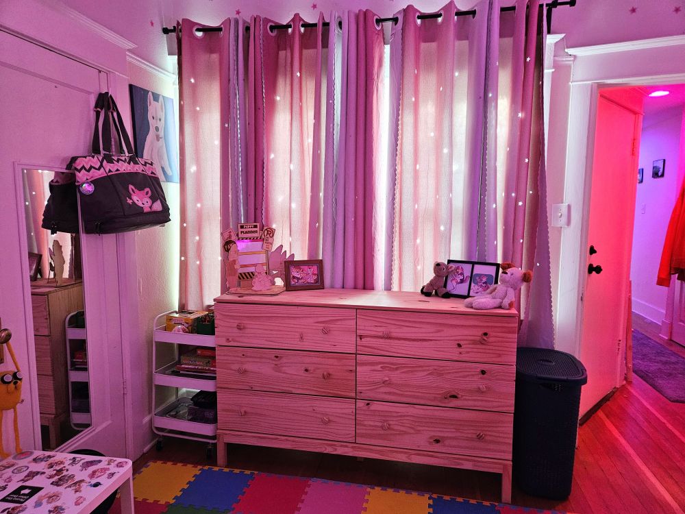 photo of a bedroom with lots of pastel pinks, lights and stuffed animals