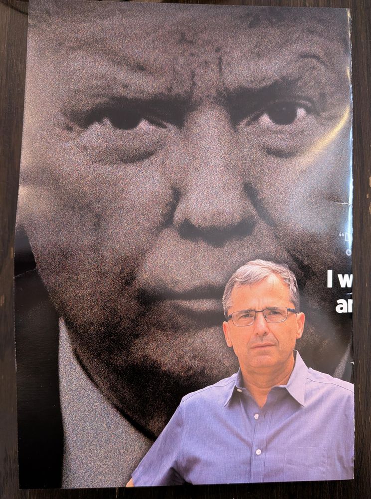 A generic looking white guy looking constipated toward the camera, with a mostly sepia photo of Donald Trump looming supportively overhead.