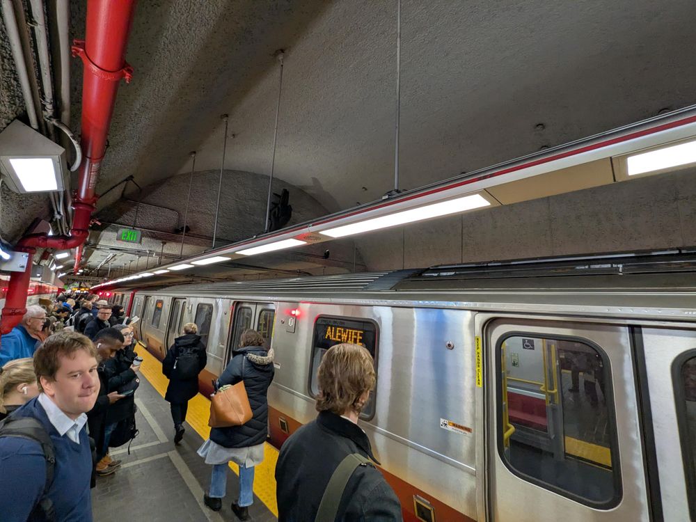A bunch of sad people next to an empty red line train
