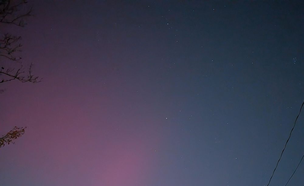 A bold whisp of red dominating a light polluted night sky. 