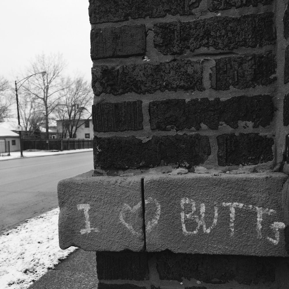 Black and white photo of graffiti along a Chicago street: "I (heart) butts"