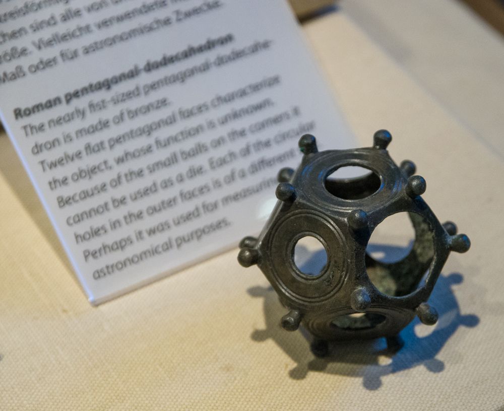 A Roman bronze dodecahedron.  It consists of 12 pentagonal bronze pieces joined at the edges to form the dodecahedron.  Each flat pentagonal side has a circular hole of a different size to all the other sides. Where three pieces meet (i.e. on the corners) is a small bronze ball.  The function of these artefacts is unknown.