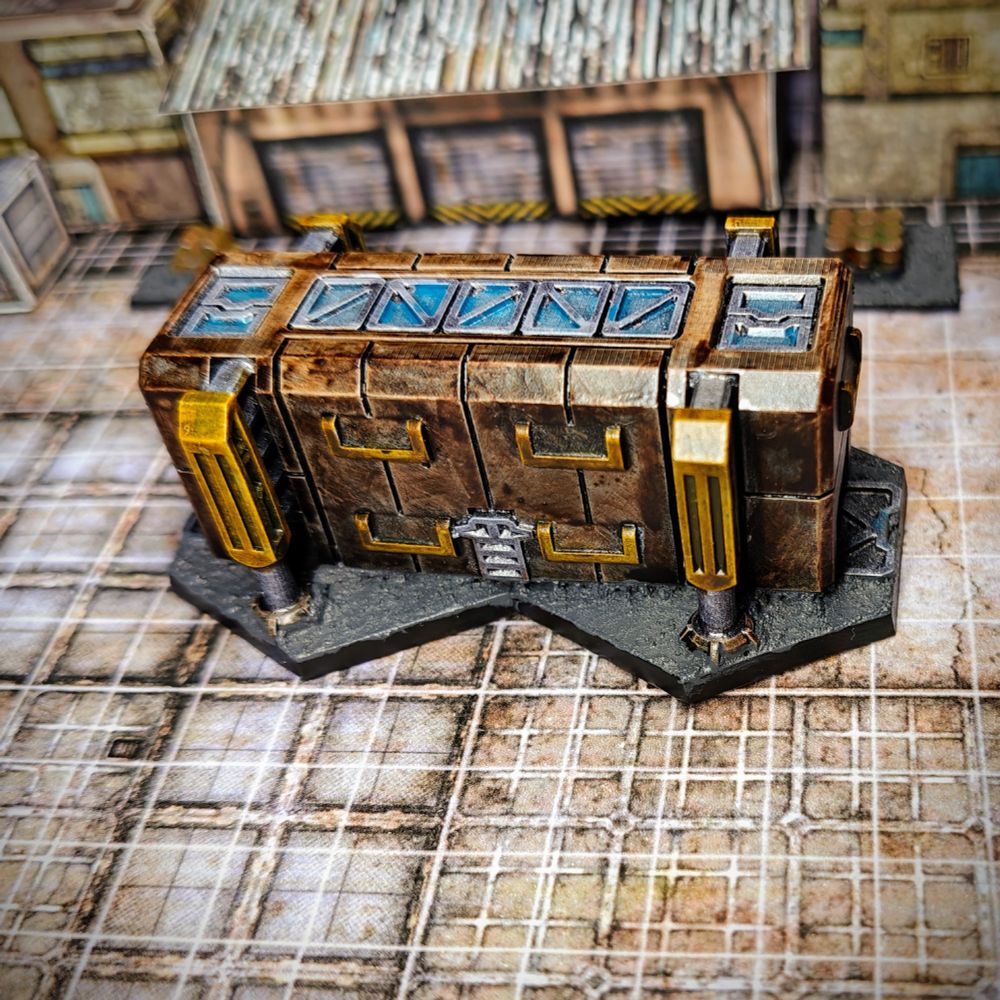 a painted 6mm scale piece of terrain, representing a building. The building is painted with brown walls and metal accents. It has a line of windows at the top and is standing on a base made of two hexagons.