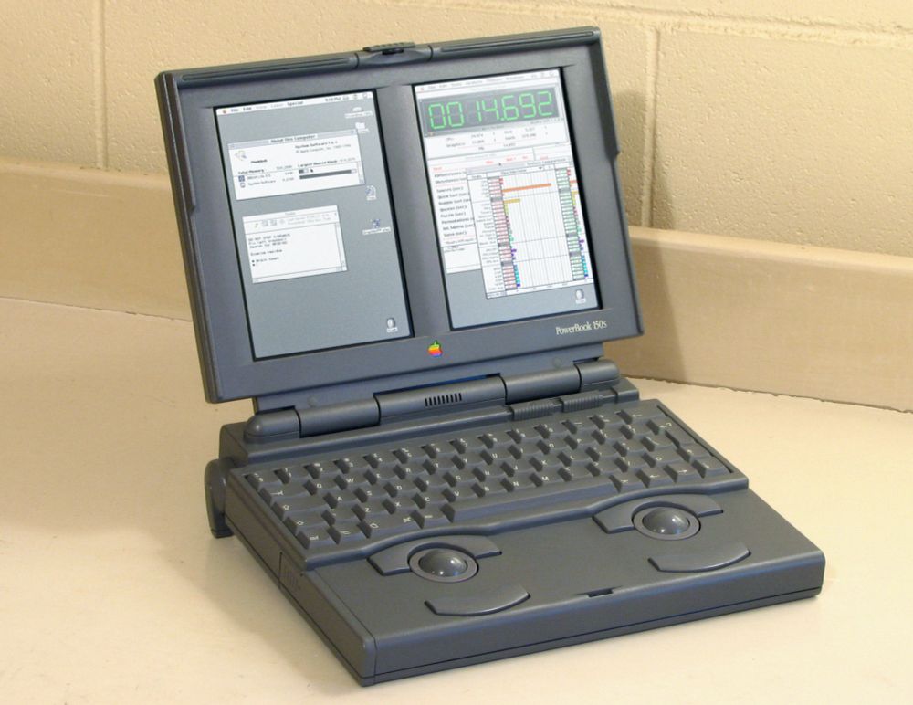 A photo of a Macintosh PowerBook 150s on a desk. The display is two portrait monitors next to one another, and below that a keyboard, with two trackballs and associated buttons below the keyboard. It looks suspiciously like a normal PowerBook 150 but extra sideways.