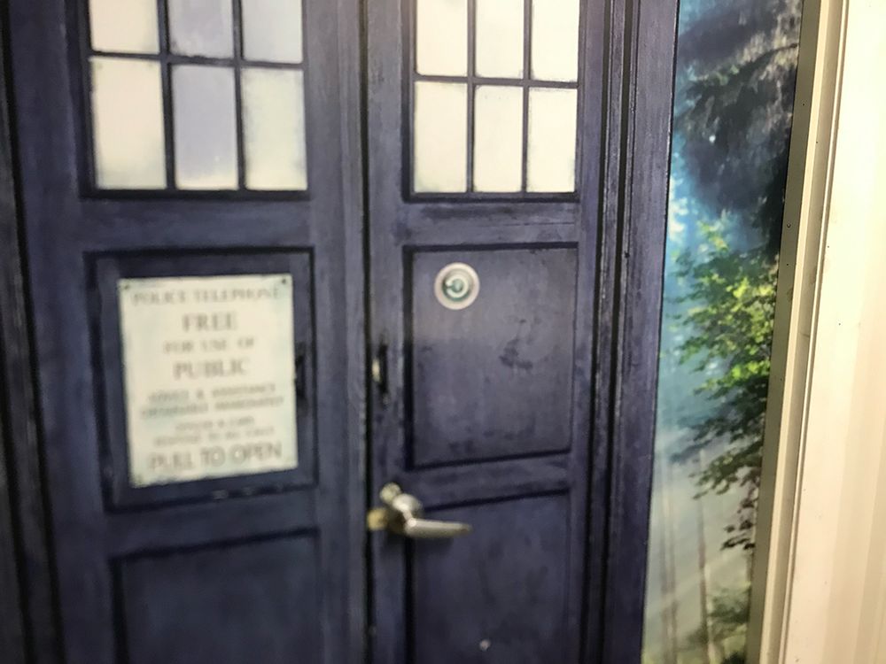 A photo of the TARDIS doors into my workplace. It's a vinyl wrap that looks just like the doctor's TARDIS from Doctor Who, and the door handle is in the lock position of the tardis. On the right hand door someone has stuck an apple Time Machine logo sticker.