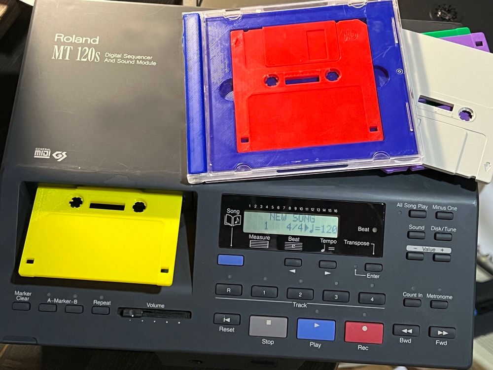 A photo of some 3.5” floppy cassettes being used in a Roland sequencer. One yellow is inserted and the other is red and still in its jewel case