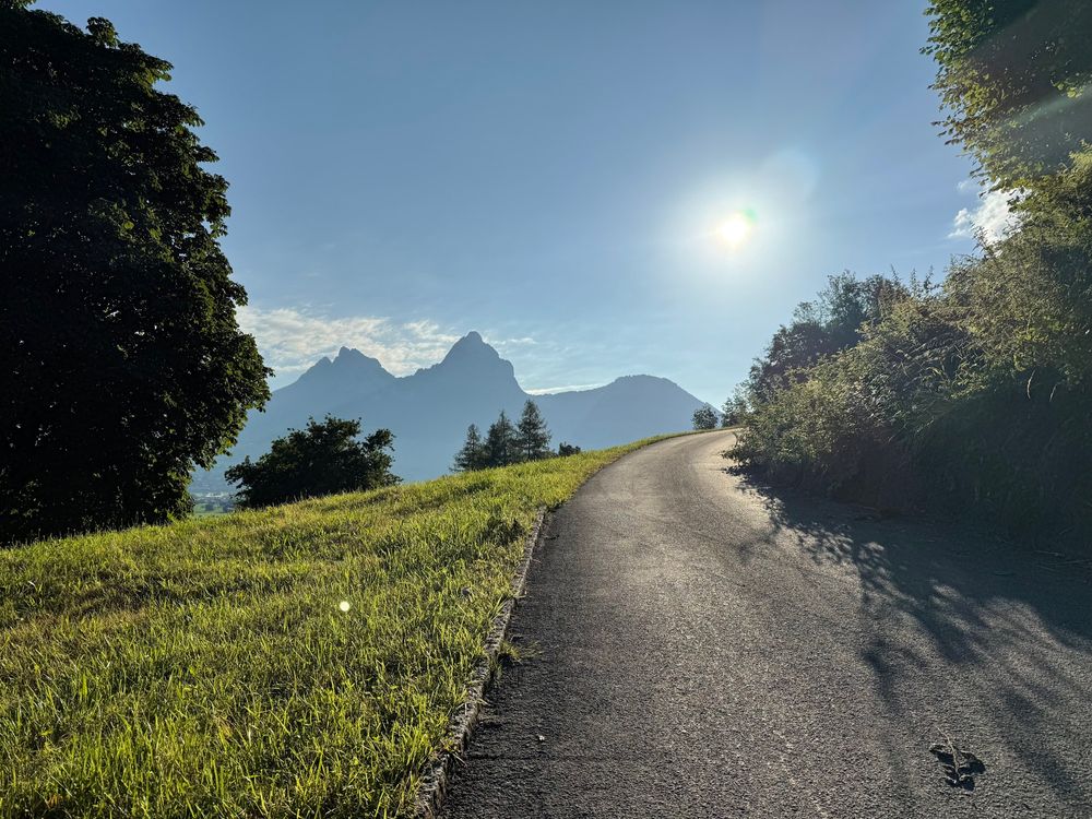 Street leadin upwards. Mountain „Mythen“ in the background. Sun shining in the blue sky. 