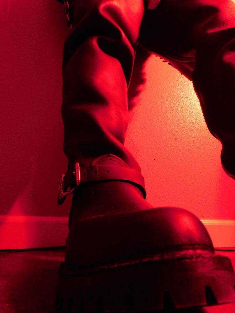 A picture of the toe and shaft of a Big Boss Wesco boot in red lighting with a branded Wesco buckle showing over the instep.