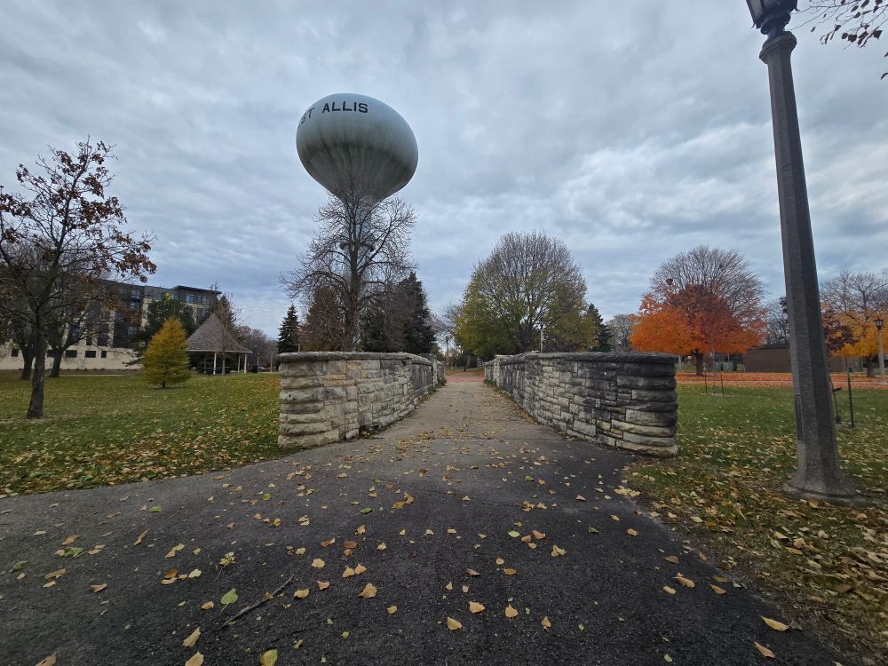 A bridge and a watertower in the background with autumn trees