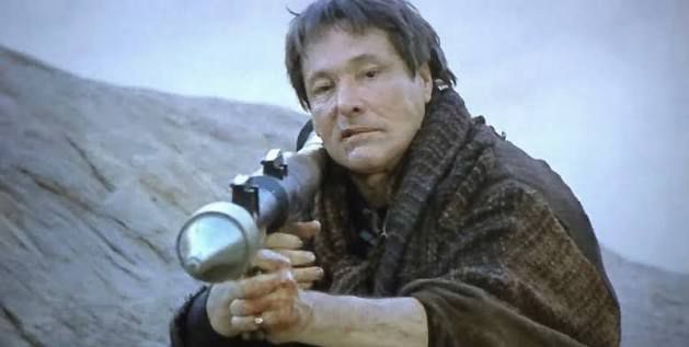William Smith wears robes and aims a bazooka