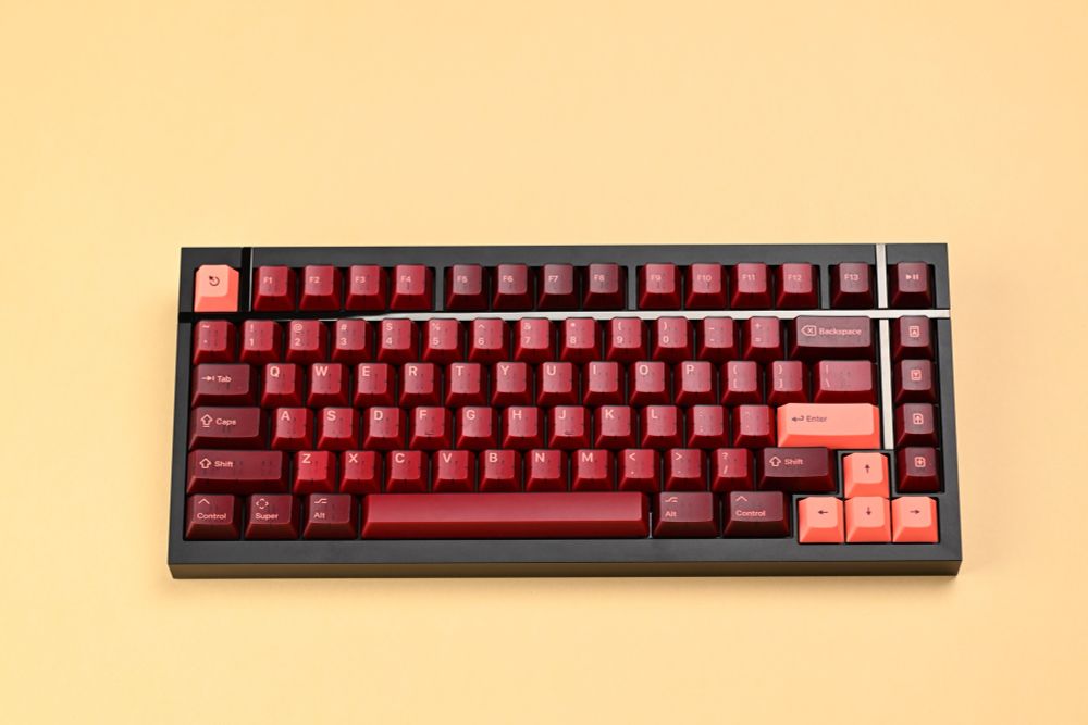 A 65% mechanical keyboard with maroon translucent keycaps with pink legends.