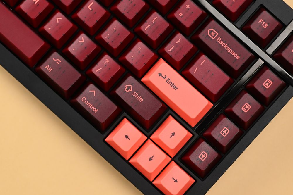 A close-up shot of part of a mechanical keyboard showing several bright pink and translucent maroon keycaps, on a black keyboard