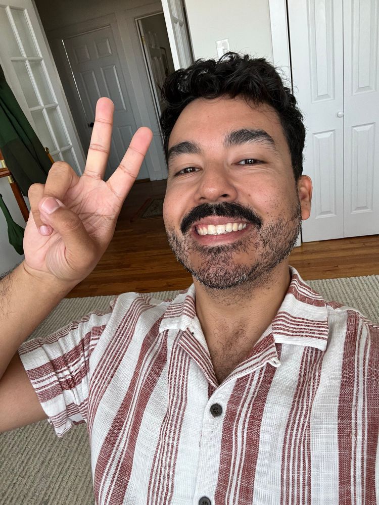 Man in a white and red striped shirt holding up a peace sign
