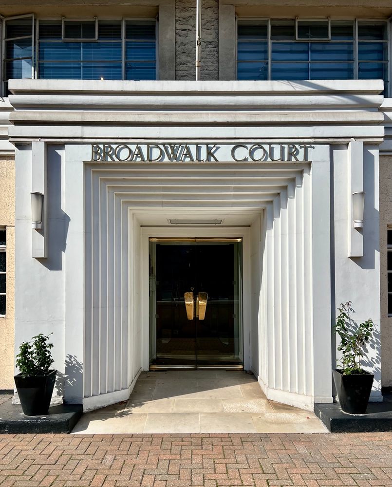 An entryway that reads “Broadwalk Court” above a deeply-stepped entryway.