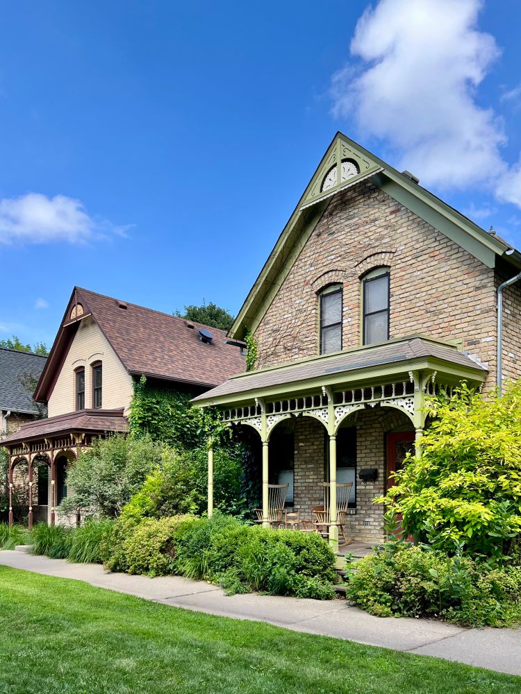 Two front gabled brick houses in a row with grass in front of them.
