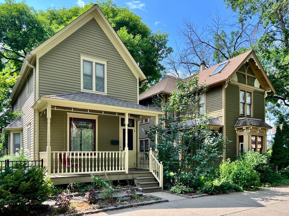 Two front gable frame houses surrounded by greenery.
