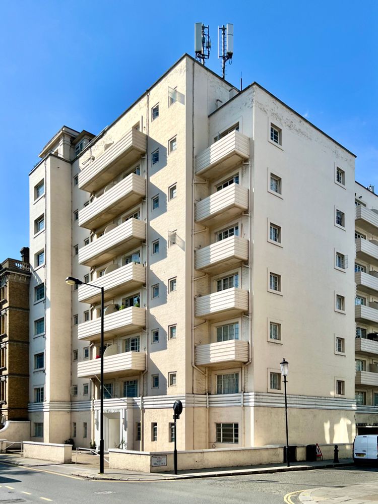 A white, mid-rise apartment building with ribbed balconies on every floor.