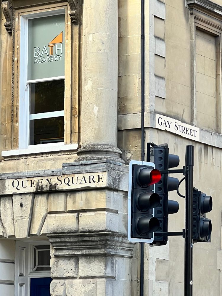 A street corner with street signs reading “Queen Square” and “Gay Street.”