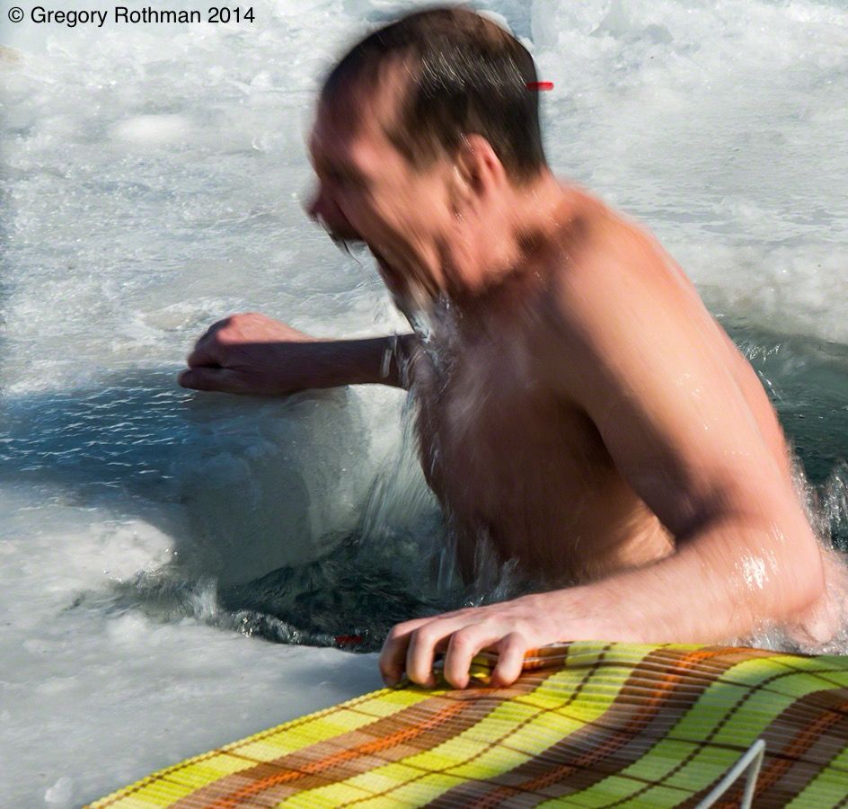 The photo captures a dramatic moment: a man is gasping for breath as he hauls himself from a jagged hole cut into 5–6 feet of solid ice on the frozen surface of Lake Baikal. His muscles are tense, veins prominent, and his face contorted in a primal reaction to the shock of subzero water. Drops of icy water fly off his body as he grips the edge of the hole and a striped mat placed on the ice for stability. This is not mere endurance—it’s ritual, tradition, and test of will.
Credit: Gregory Rothman 2014 

We had finished up Ice Diving for the day when this was offered. Only a couple people got in. My Russian friends, who did not participate,  encouraged me to try it. They said “It feels good afterwards. It’s good for you.” I responded, “it feels good when someone stops punching you in the face.”

Lake Baikal – Sacred, Ancient, and Brutally Beautiful
	Location: Southeastern Siberia
	Depth: 1,642 meters (deepest in the world)
	Winter Freeze: From January to April, the lake freezes over with ice 1–2 meters thick—so clear in places you can see 40 meters down.
	Ecology: Over 80% of its species are endemic, including the Baikal seal (nerpa), the only freshwater seal in the world.
	Heritage: A UNESCO World Heritage Site, Lake Baikal is sacred to local Indigenous groups and beloved across Russia for its purity and power.
