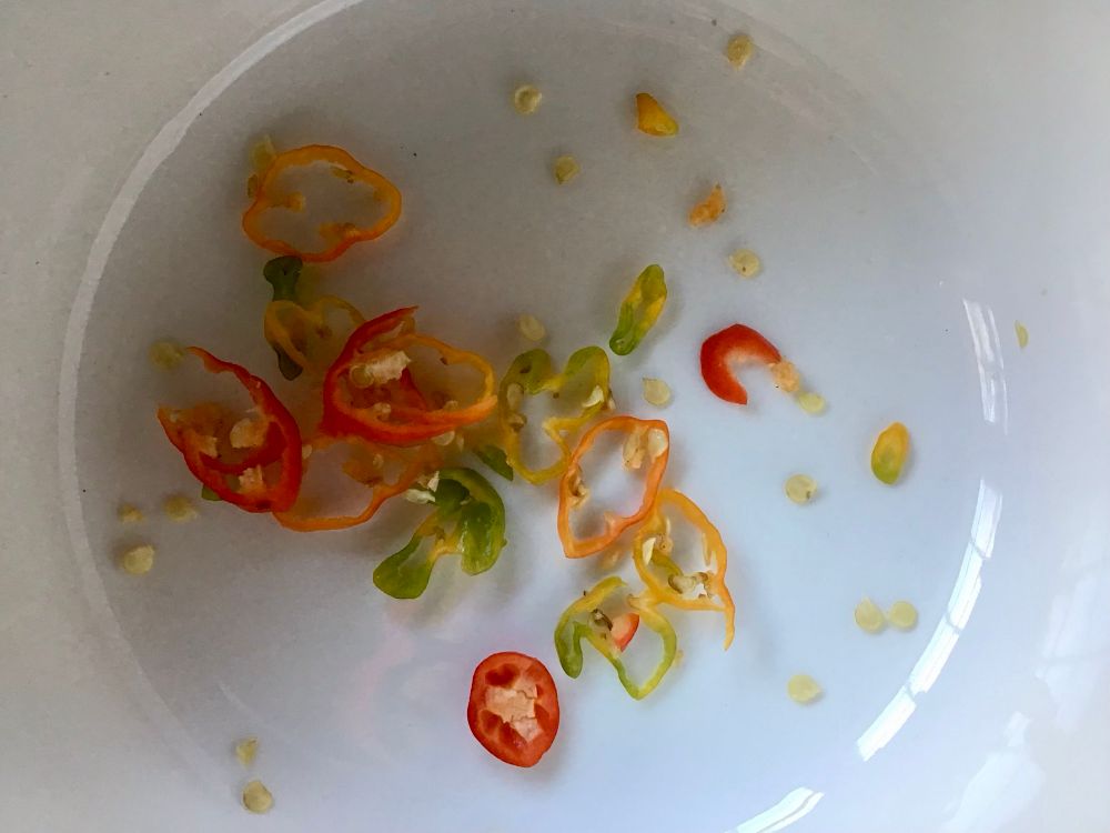 Thin slices of orange, red, yellow, and green ghost pepper