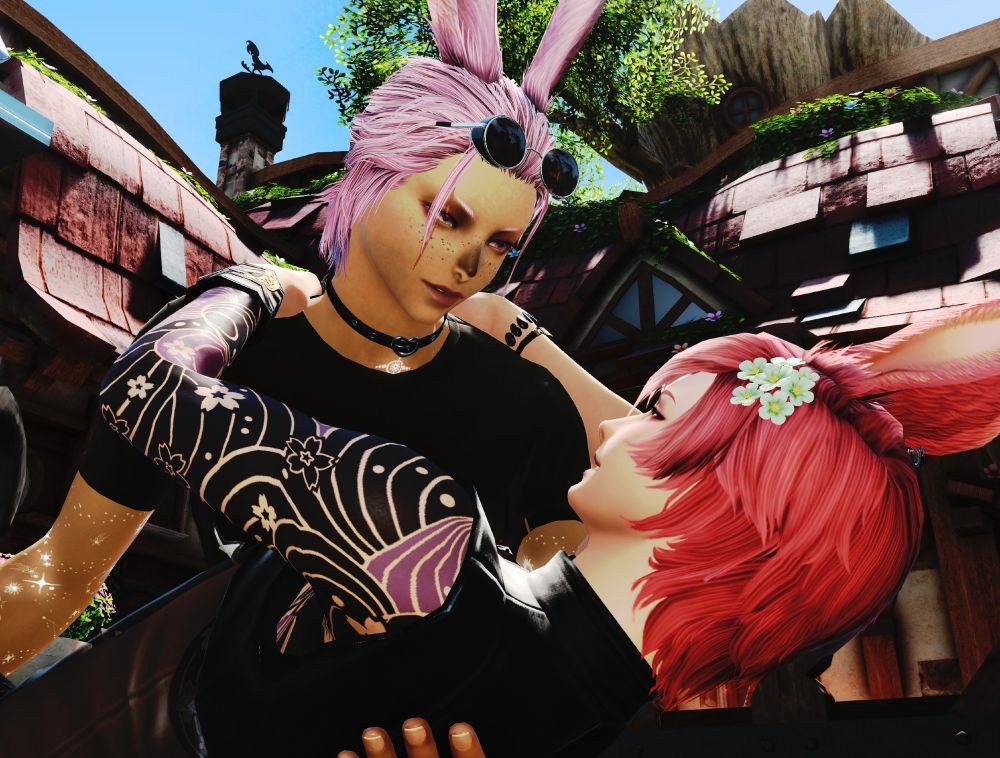 Two male Viera embrace romantically. The pink-haired viera (weaing a black t-shirt, black leather collar, and with black circular sunglasses lifted onto his forehead) dips the red-haired Viera (wearing a black Oriental-style top and with flowers in his hair).