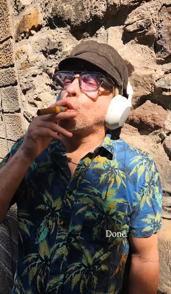 RHYS DARBY IN THE SHIRT IN THE CHAIN SMOKING A CIGAR
