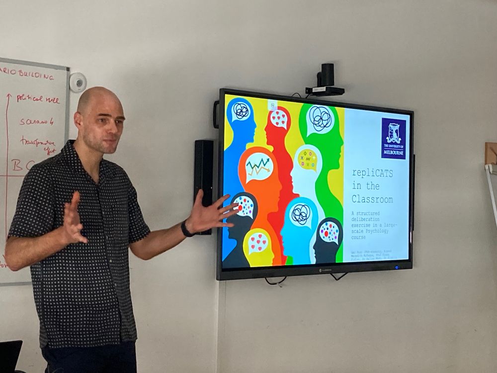 Ger standing in front of the title slide of his presentation