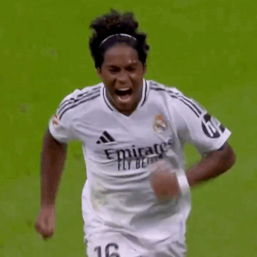 a soccer player wearing a white emirates fly better jersey is running on a soccer field .