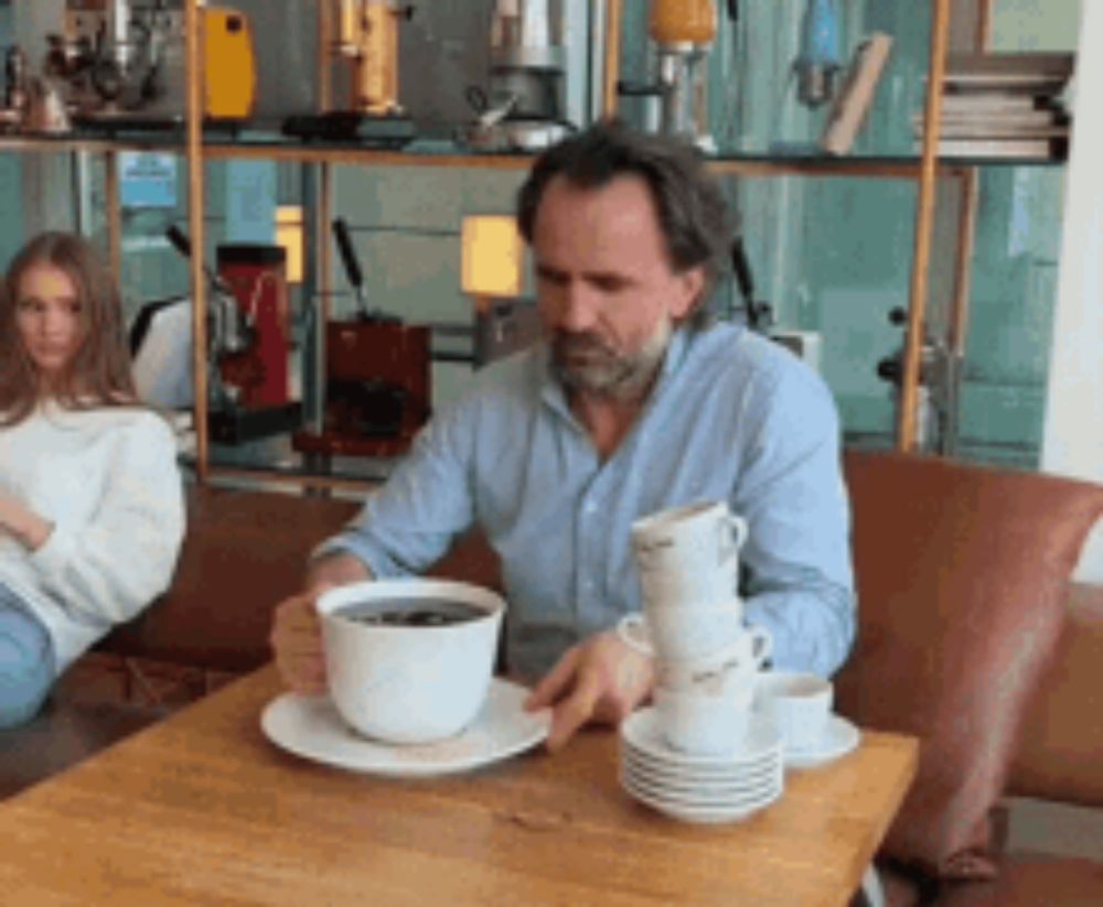 a man is sitting at a table with a cup of coffee on it