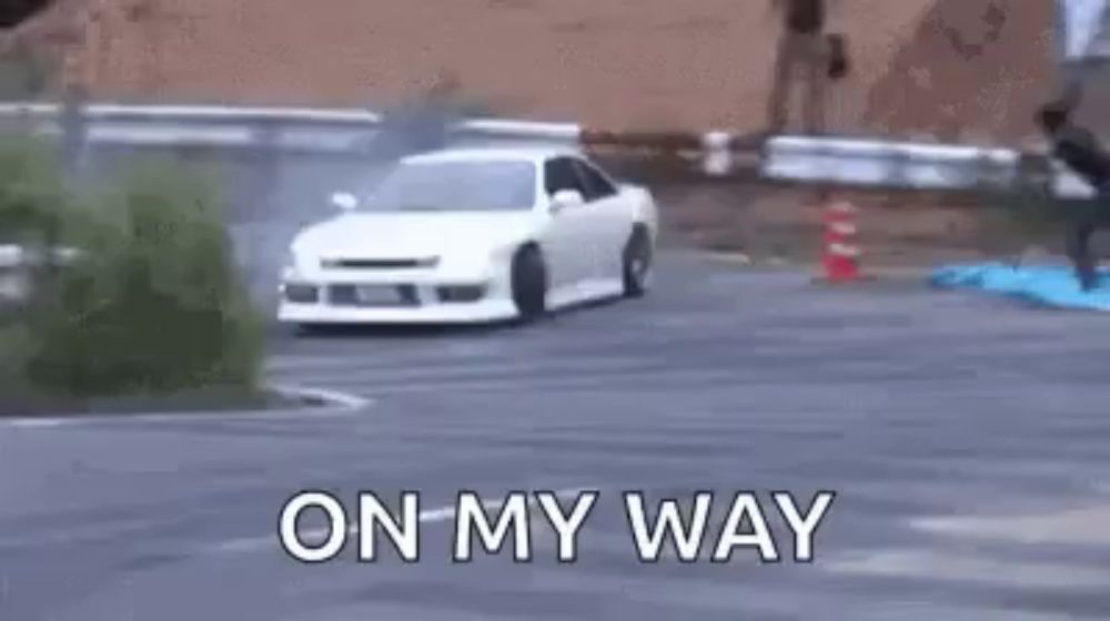 a white car is drifting on a road with the words `` on my way '' written on the bottom .