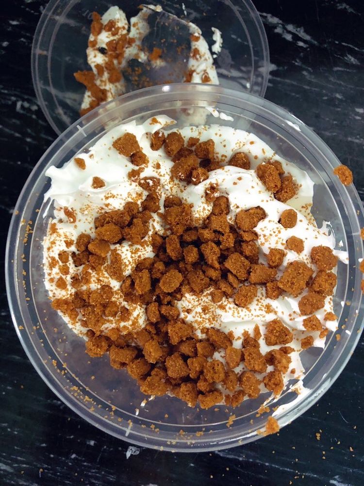 Looking down on a plastic pottle with marshmallow fluff topped with Biscoff crumbs. www.whiskandspoon.co.nz