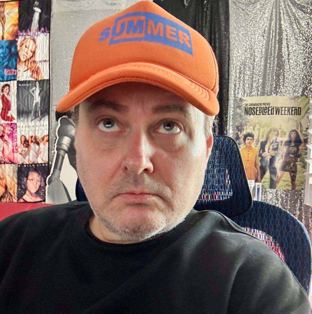 Me, comedían/writer/editor/host/lover/friend Adam Tod Brown, wearing a hat that just says “Summer” on it 