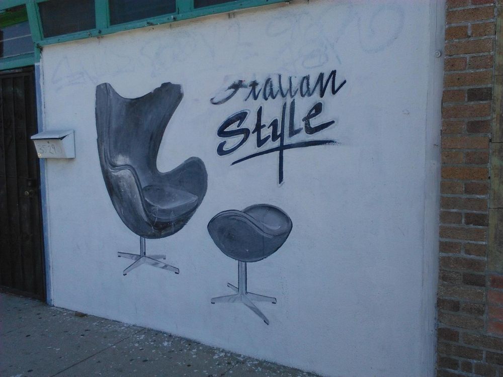 A wall painted as an advertisement, with a chair and the words "Italian Style" in cursive
