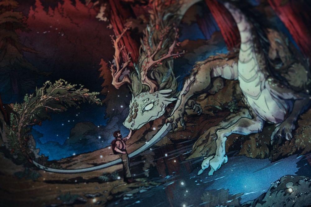 A card game playmat featuring an autumn forest with a woodland dragon and a bearded hiker featured prominently.