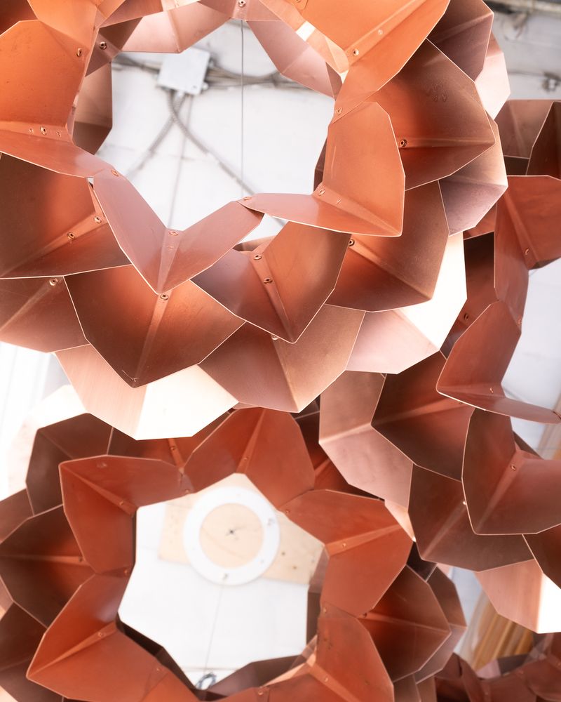 Detail looking straight up at the overlapping copper petals of three pendants.