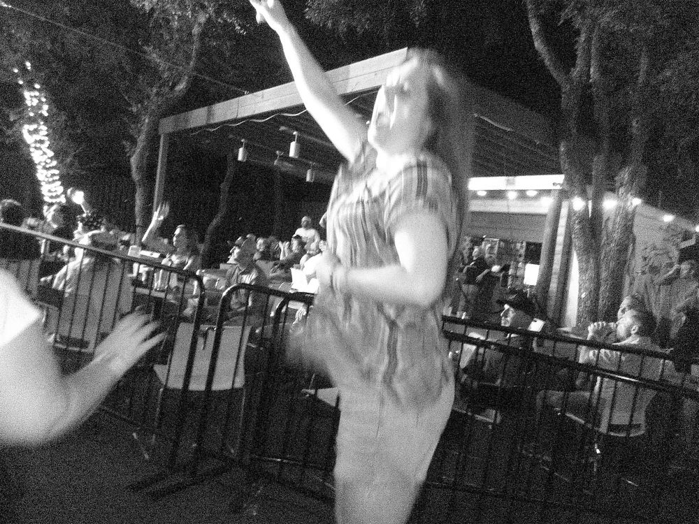 Blurry picture of woman in plaid shirt jumping with one arm in the air 