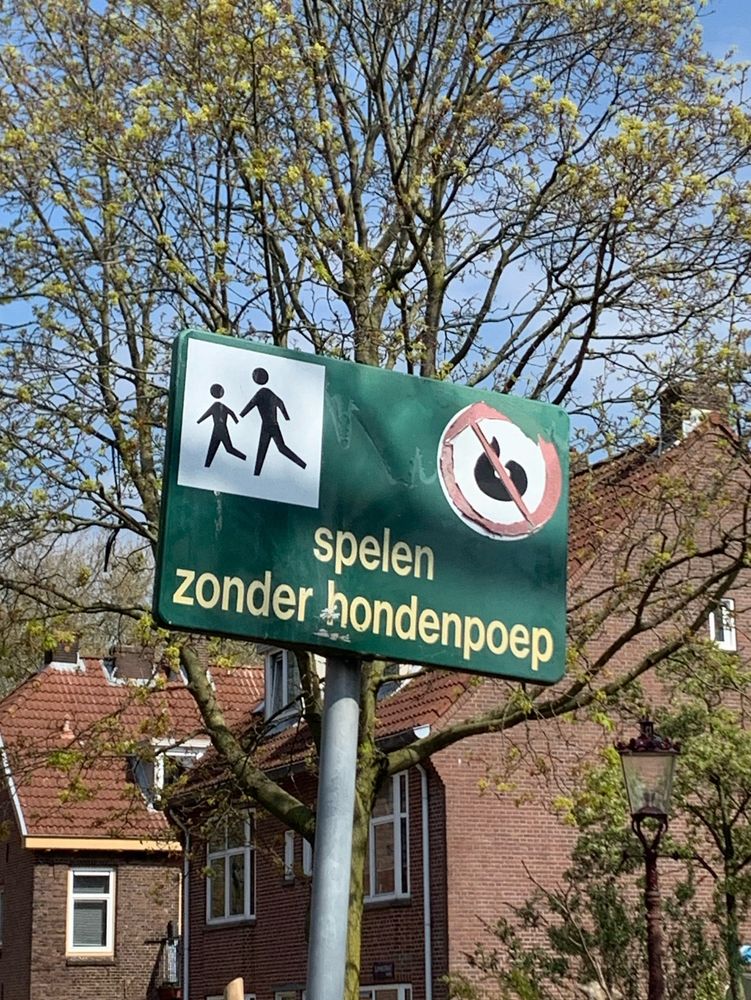 Een bord bij een speeltuin, met daarop de tekst: spelen zonder hondenpoep