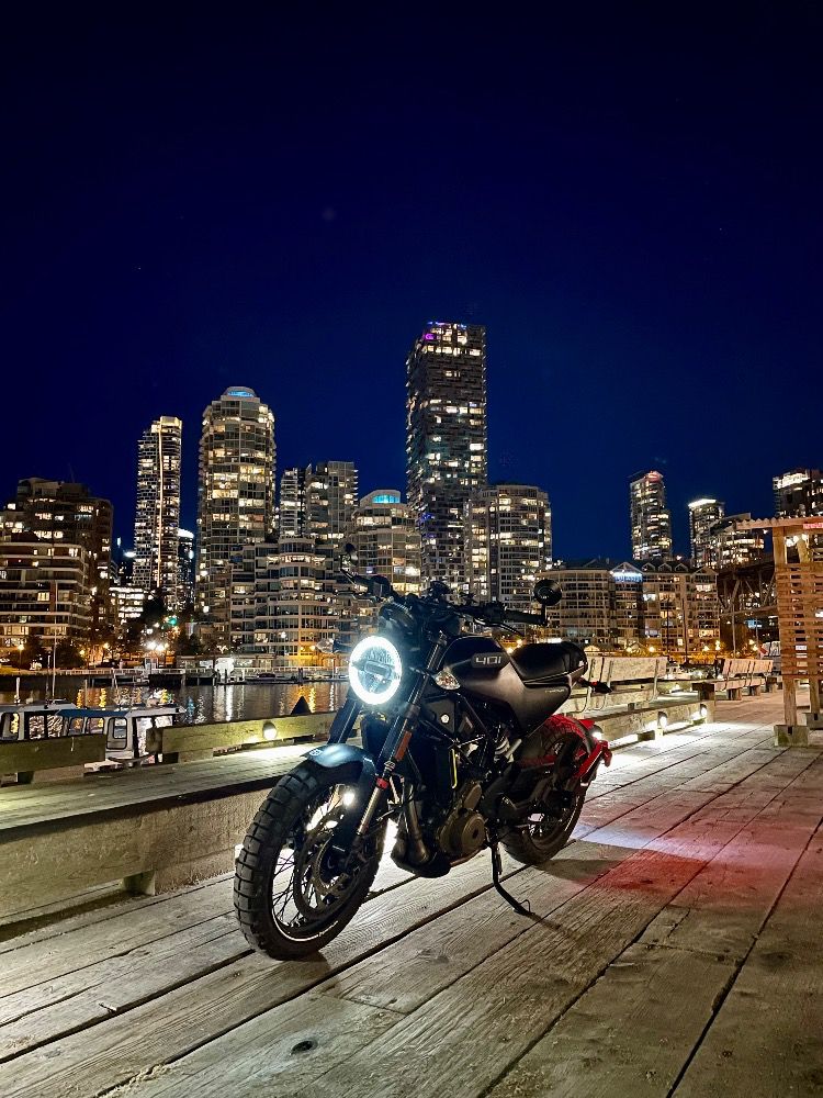 Motorcycle at night with part of the Vancouver skyline in the background