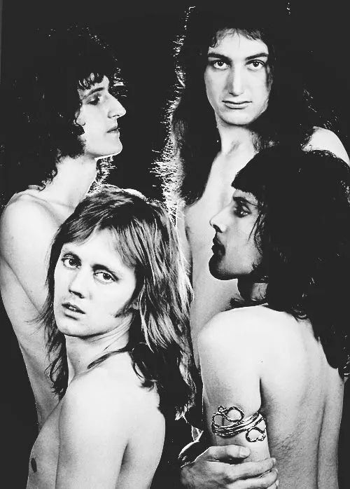 the members of queen (clockwise: freddie mercury, roger taylor, brian may, and john deacon) all shirtless in a black-and-white photoshoot