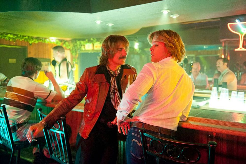 Scott Bakula and Matt Damon in the film Behind The Candelabra standing in a bar in the 1970s. 