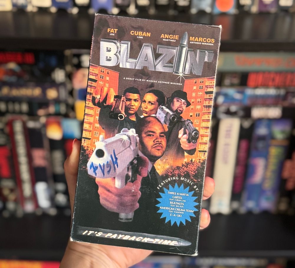 A vhs tape of the movie Blazin’ with rapper Fat Joe holding a gun and three others behind him also holding guns with two buildings between them. 