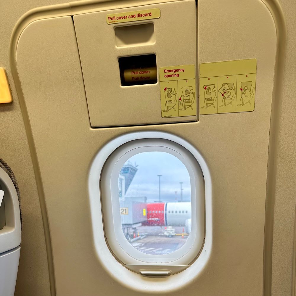 Kuva ulos lentokoneen ikkunasta hätäuloskäynnin kohdalta, ikkunasta näkyy Norwegian-yhtiön lentokone.