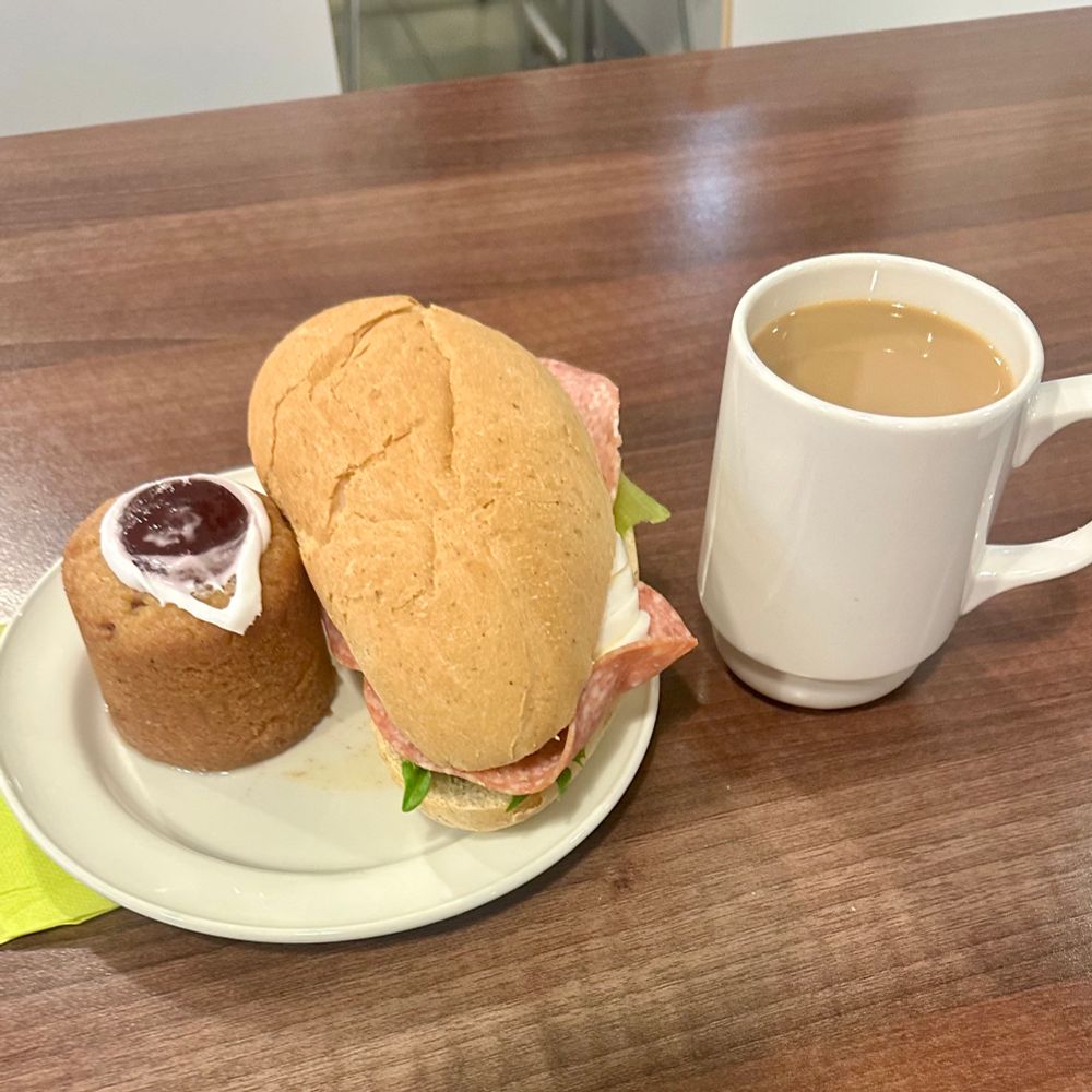 Lautasella runebergintorttu ja sämpylä, vieressä kuppi kahvia