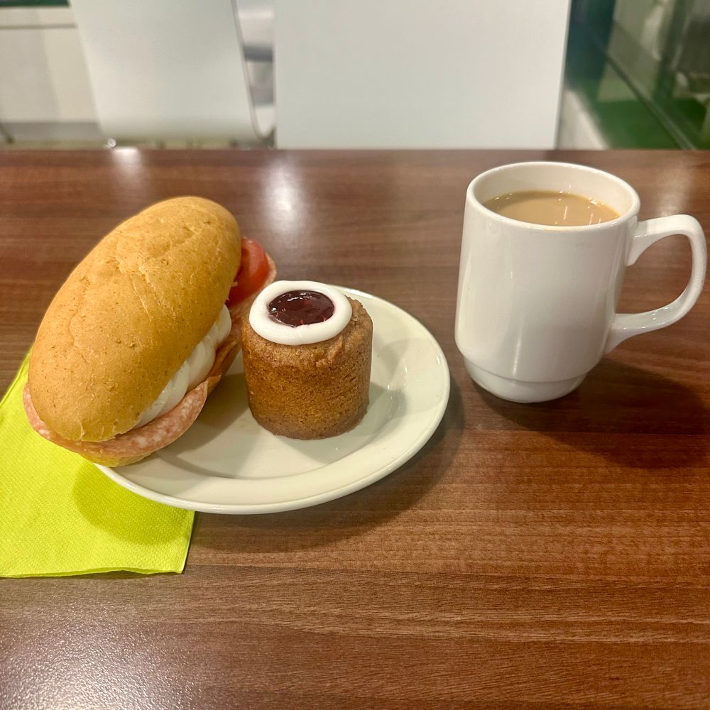 Lautasella sämpylä ja runebergintorttu, vieressä kuppi kahvia.