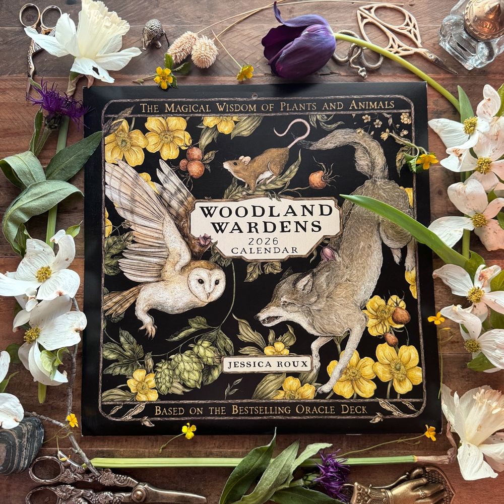 Photo of the 2026 Woodland Wardens Calendar, on a wooden desk surrounded by flowers 