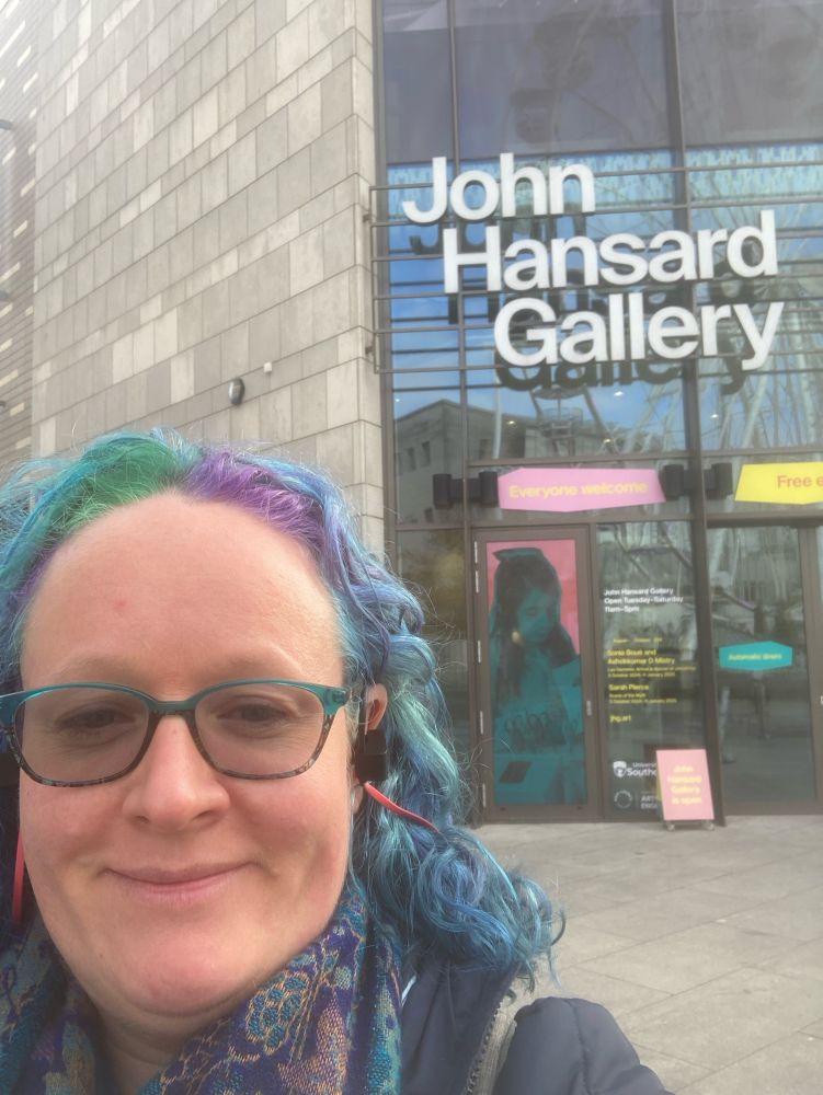 A woman with blue, purple and green hair in front of the John Hansard art gallery.