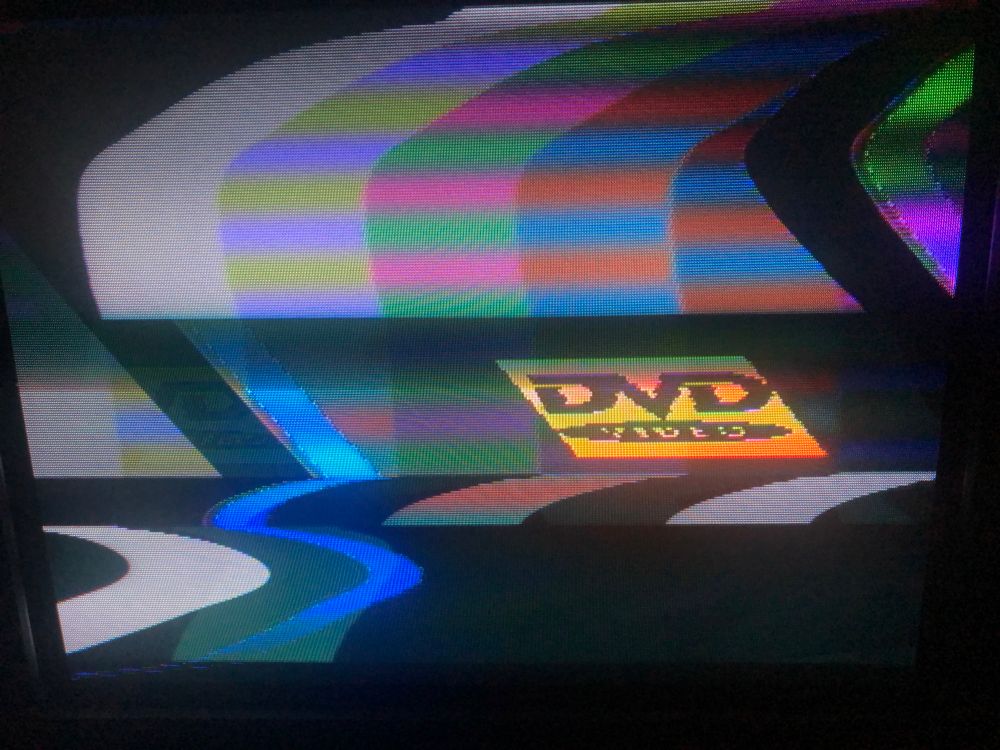 photo of my 90s Panasonic CRT TV displaying two video sources over the top of each other - colour bars and an NES demake of the bouncing DVD logo