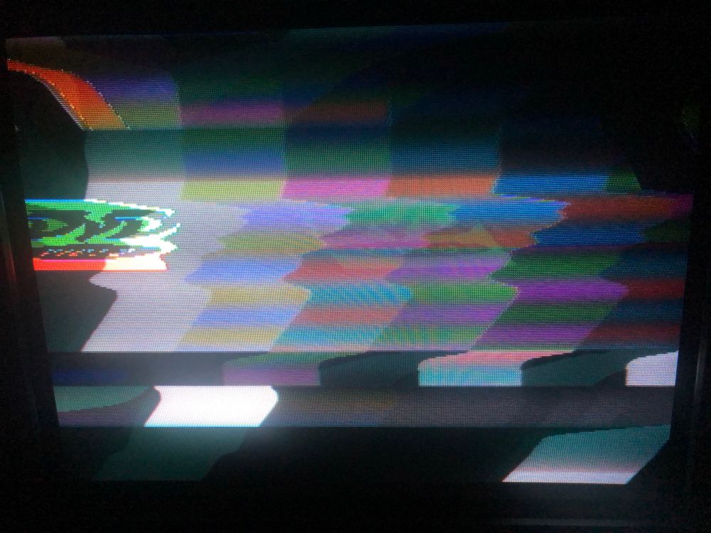 photo of my 90s Panasonic CRT TV displaying two video sources over the top of each other - colour bars and an NES demake of the bouncing DVD logo