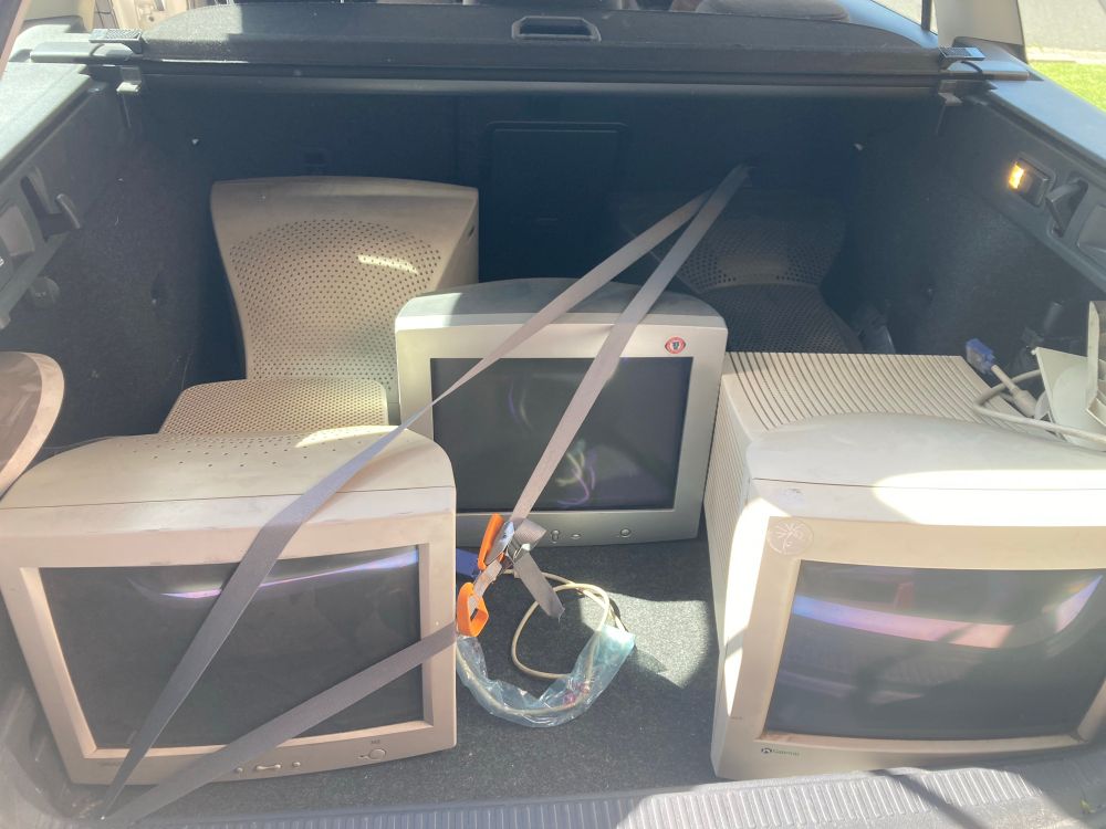 five more CRT monitors in the boot of the car, one held in place with straps so that it doesnt slide into the little bit of extra space to its side